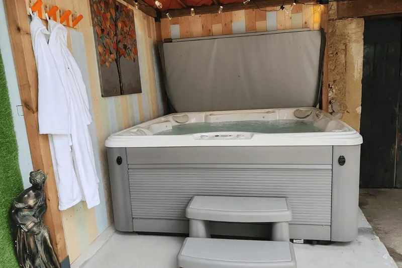 Spa Caldera Marino vu de face dans la cour, marchepied devant, peignoirs accrochés au mur