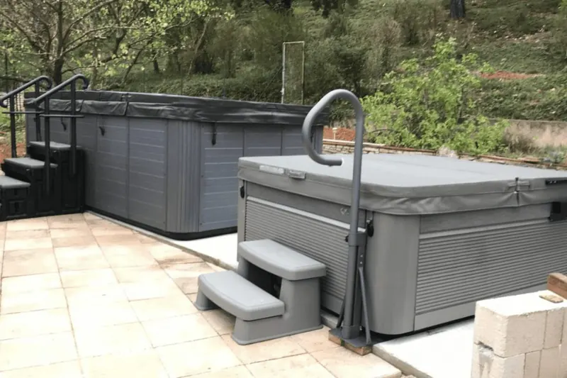 Spa extérieur six places sur une terrasse dallée à Alès, barre d'appui et marchepied devant