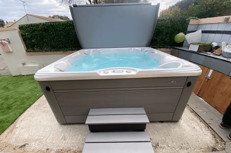 Grand spa Caldera Palatino rempli dans un jardin de Prades-le-Lez, couvercle relevé