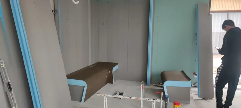 Intérieur du hammam en construction, avec lits de repos marron et parois gris clair