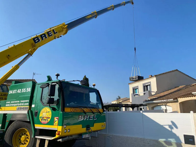 Camion-grue BREL dans la rue, spa suspendu au-dessus du mur de clôture