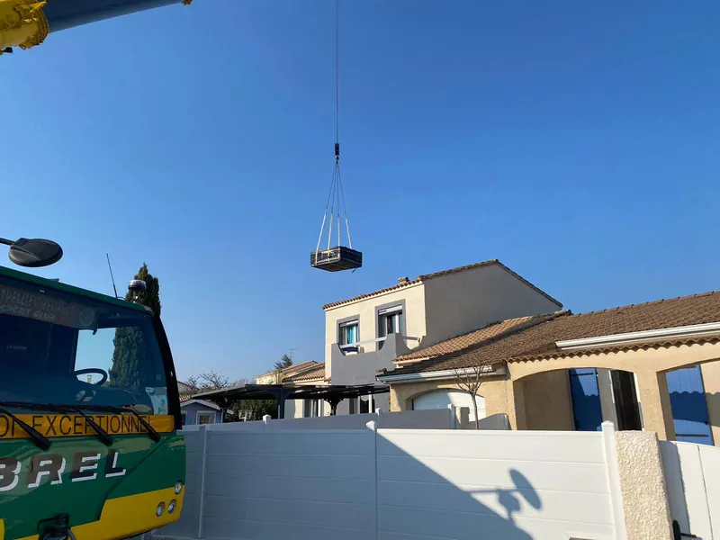 Spa suspendu à la grue au-dessus des toits avant sa descente sur la terrasse