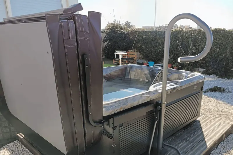 Couvercle replié sur le côté du spa Caldera Celio, barre d'appui en inox devant