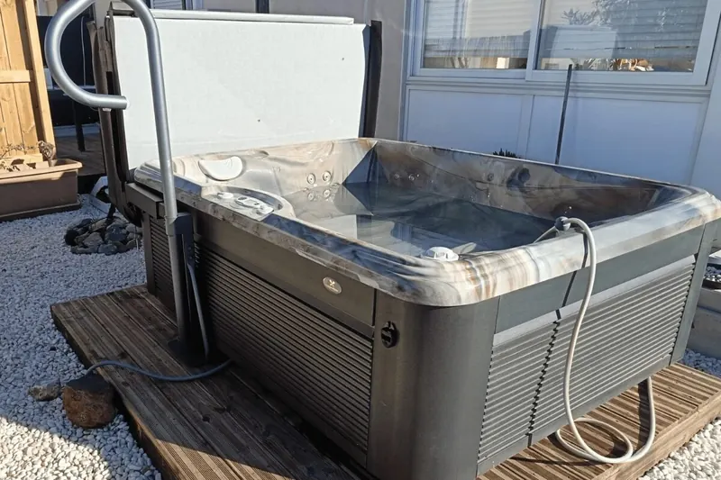 Spa Caldera Celio installé sur sa terrasse en bois à Leucate, couvercle relevé
