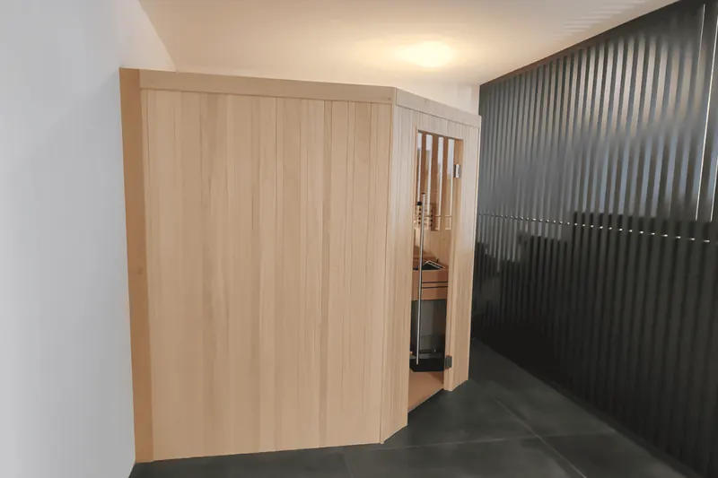 Cabine de sauna finlandais en bois clair montée dans l'angle d'une pièce