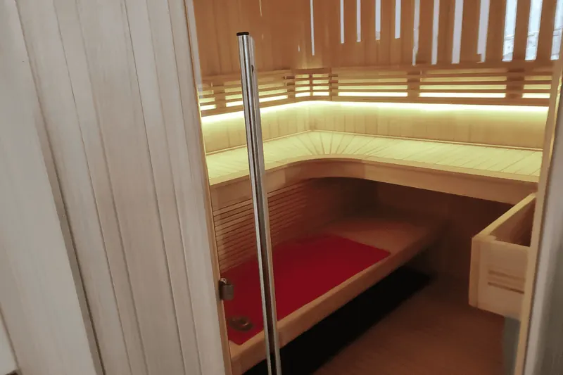 Intérieur du sauna d'angle avec ses banquettes éclairées par un bandeau LED