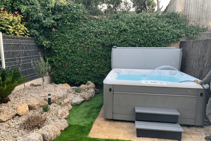Vue d'ensemble du jardin avec la rocaille, le gazon et le spa rempli