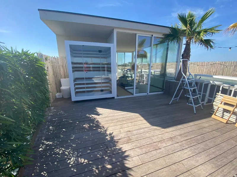 Cabine de sauna vitrée sur la terrasse, clôture en bois derrière