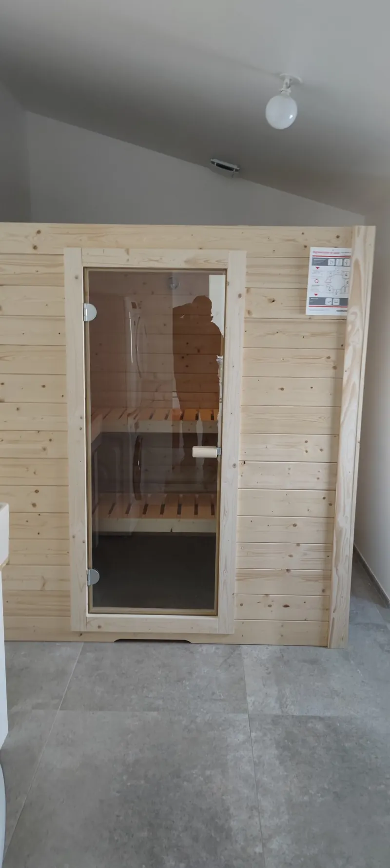 Porte blanche fermée donnant accès au sauna en bois, vue de l'extérieur