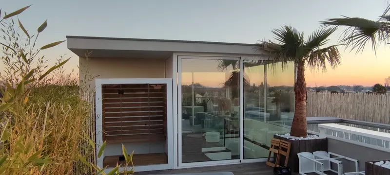Terrasse avec sauna, spa et piscine devant la maison, au crépuscule