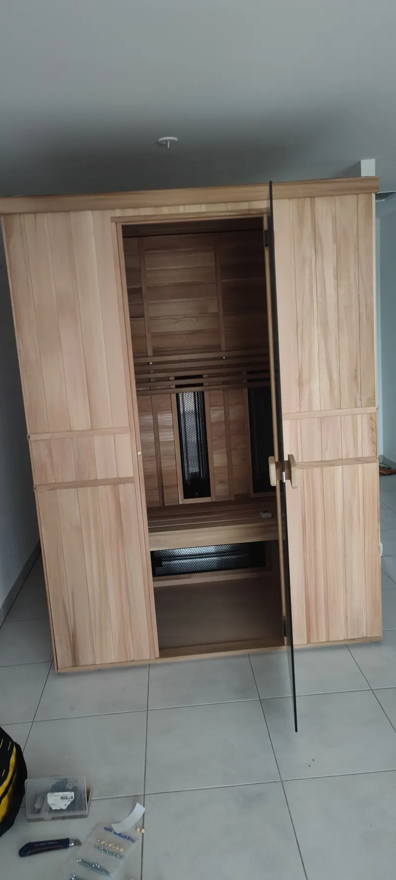 Sauna en bois clair aux portes ouvertes, vue intérieure