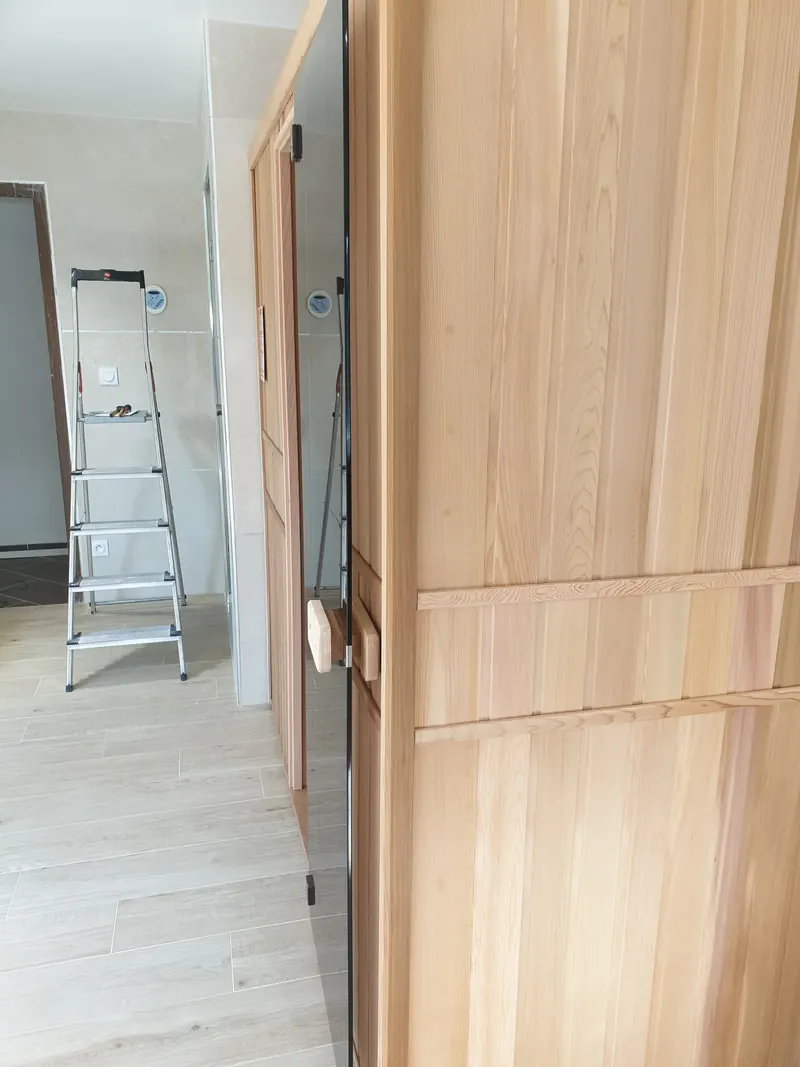 Flanc du sauna en bois et escabeau dans la pièce carrelée, à Vic-la-Gardiole