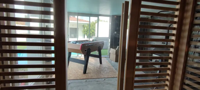 Porte du sauna à lames fines et espacées, vue de côté, avec l'accès vers la piscine