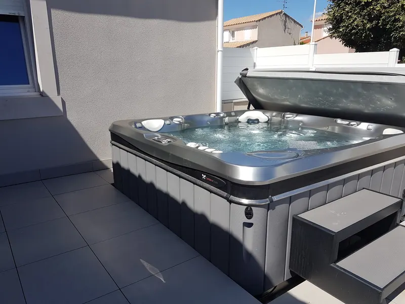 Spa Caldera Geneva ouvert, eau en mouvement, le long du mur d'une maison sur terrasse carrelée