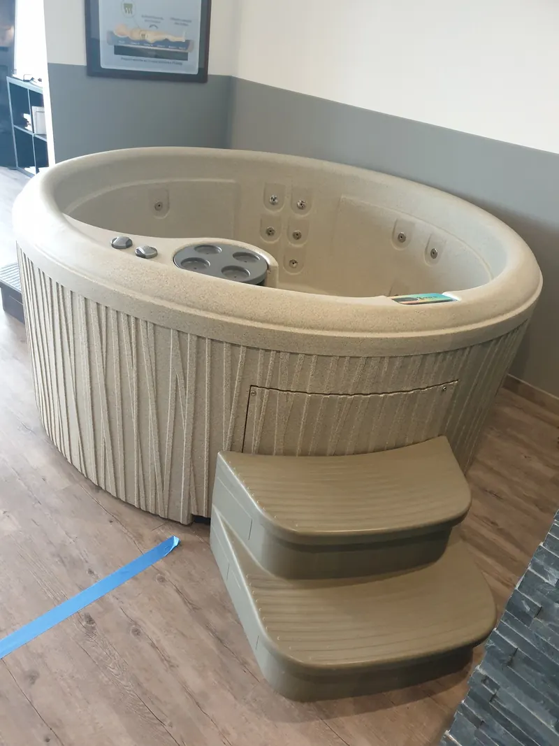 Spa ovale crème avec ses marches en bois naturel, dans un espace intérieur lumineux