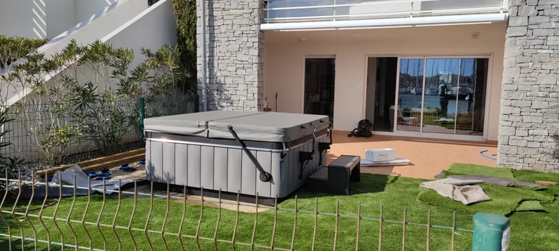Spa blanc et gris enveloppé, en cours de mise en place sur la terrasse côtière