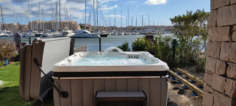 Spa blanc rempli d'eau, avec les murs de la maison autour