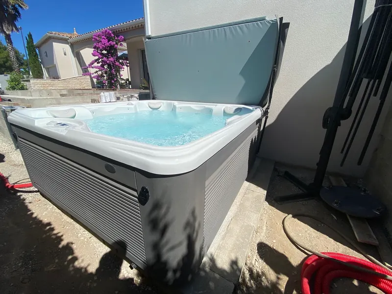 Spa dans la cour étroite, devant la maison blanche et des fleurs violettes