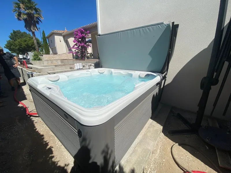 Spa en place dans la cour, avec l'habitation, un palmier et des fleurs