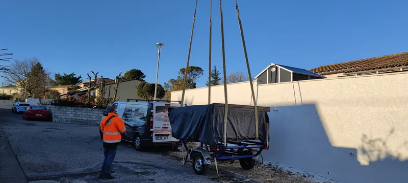 Spa sous bâche sanglé et accroché aux chaînes de la grue, sur sa remorque