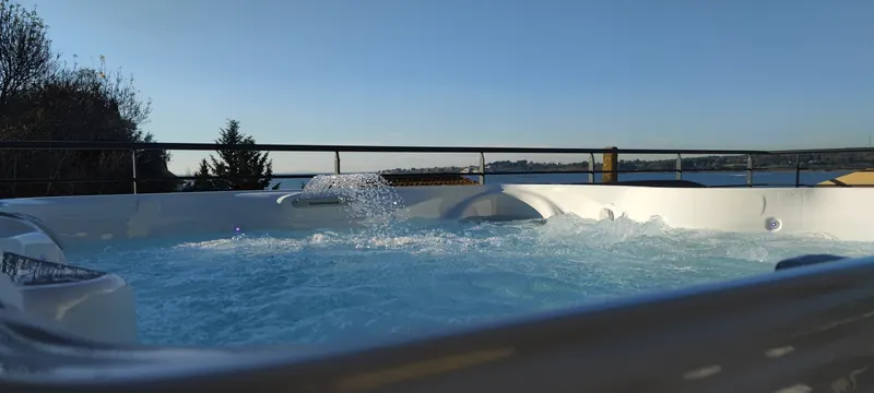 Jet d'eau en cascade dans le spa, garde-corps et plan d'eau au loin