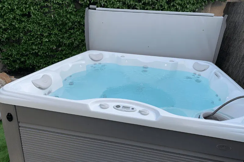 Spa en eau, jets en marche et clavier de commande sur la margelle, à Saint-Jean-de-Védas