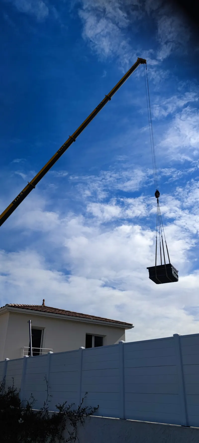 Spa descendu à la grue, maison et clôture à l'arrière-plan