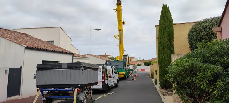 Grue jaune levant le spa dans une impasse étroite entre des murs