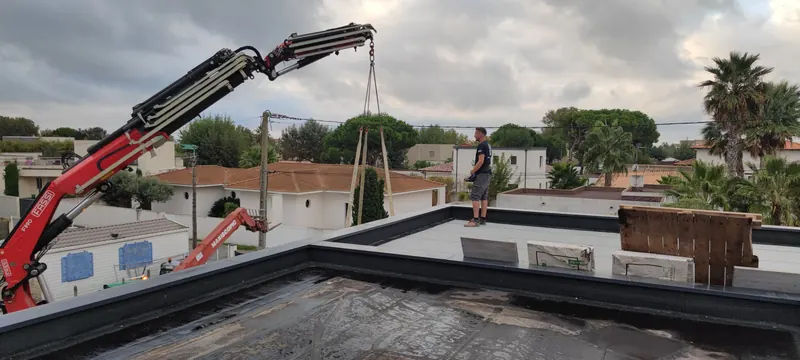 Grue rouge levant le spa blanc et noir au-dessus d'une maison, vue latérale du chantier