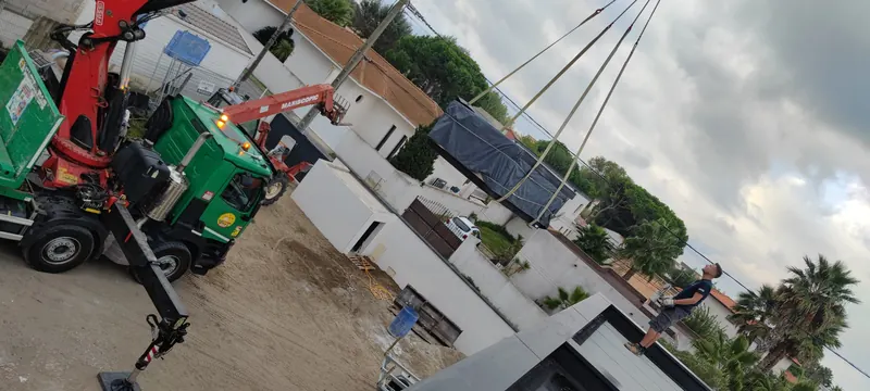 Levage du spa à la grue rouge, avec la maison blanche et la route d'accès
