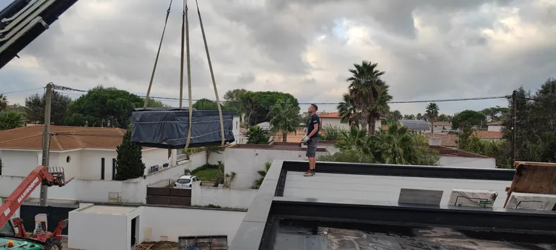 Spa protégé par une bâche bleue, suspendu à la grue en position horizontale