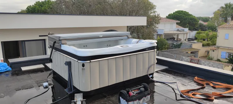 Spa blanc, couverture fermée, posé sur la terrasse surélevée avec une vue dégagée