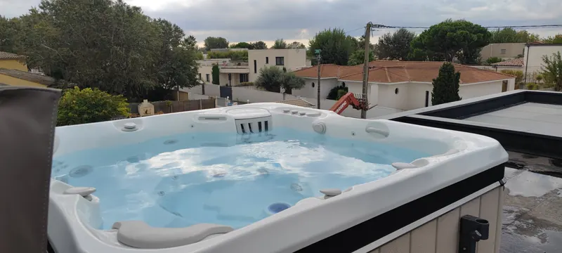 Vue de haut du spa en fonctionnement, accès à la terrasse et piscine en arrière-plan