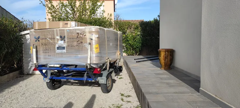 Spa Caldera sous emballage plastique sur un chariot de manutention bleu, devant une maison