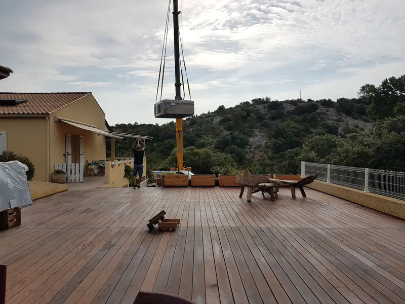 Spa emballé suspendu à la grue au-dessus d'une terrasse en bois à Saint-Paul-et-Valmalle
