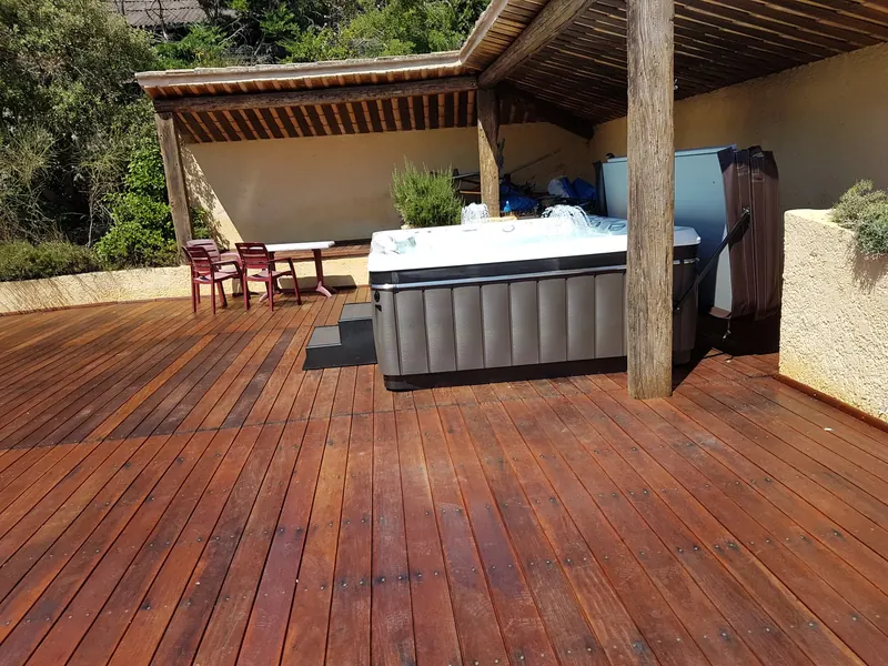 Spa installé sous un abri à poutres de bois, au bord d'une grande terrasse à Saint-Paul-et-Valmalle