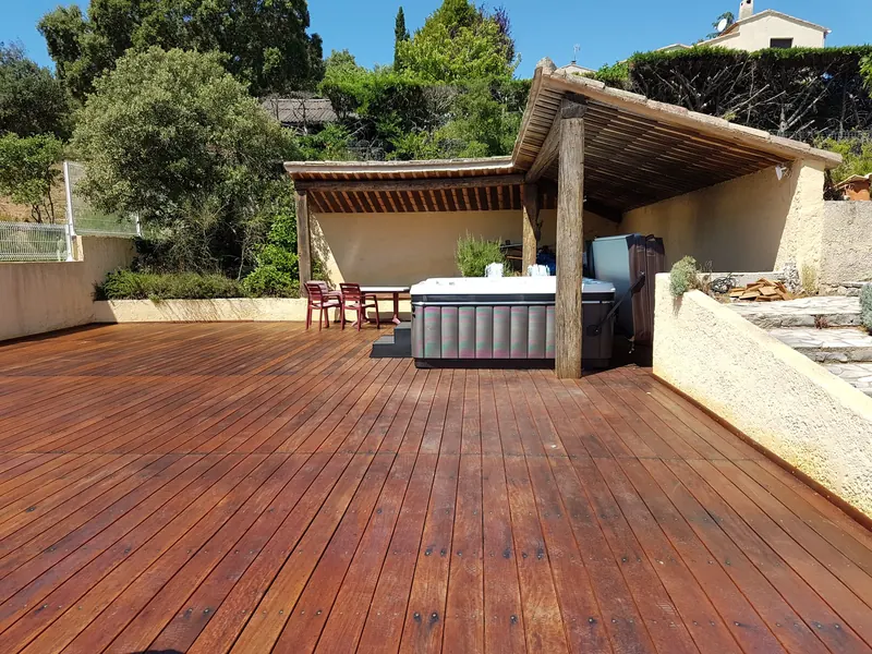 Vue large de la terrasse en bois et de l'abri où le spa est installé à Saint-Paul-et-Valmalle