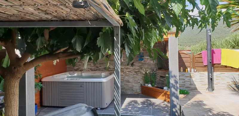 Spa installé sous l'abri, vu depuis la pergola en canisse près d'une douche extérieure à Vic-la-Gardiole