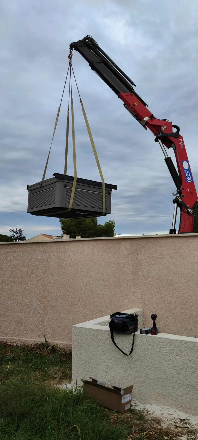 Spa suspendu à ses câbles de grue, au-dessus d'un terrain pavillonnaire