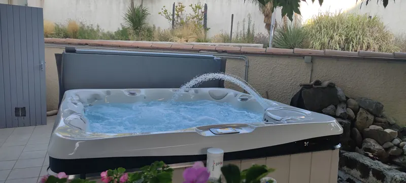 Spa Caldera rempli d'eau, accessoires visibles, sur une terrasse ombragée