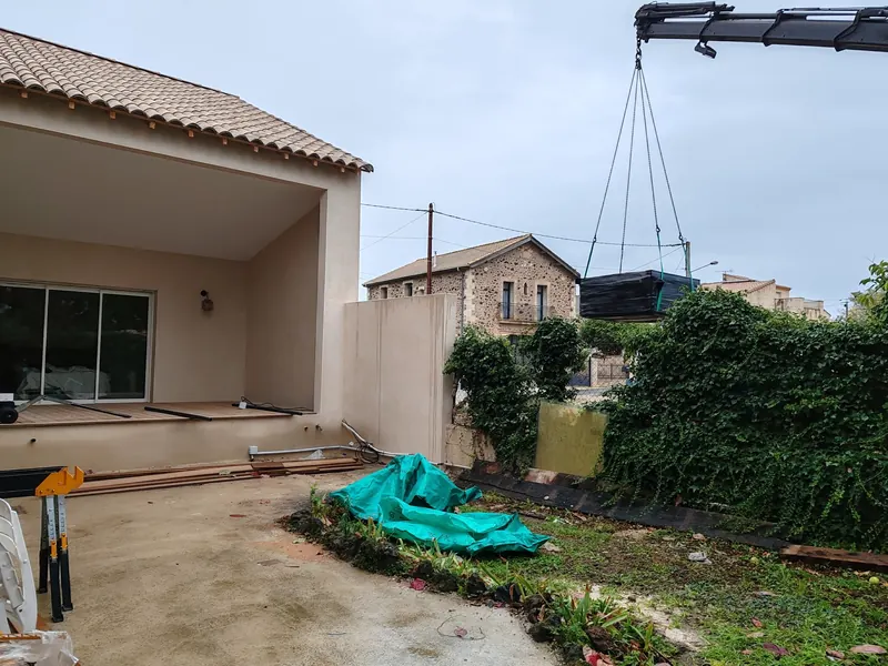 Spa suspendu à la grue près d'une maison à terrasse couverte et baie vitrée coulissante