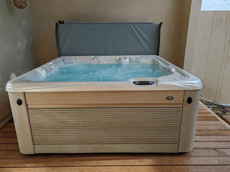 Spa rempli d'eau, couverture relevée, jet d'eau en arc et badge Caldera Spas