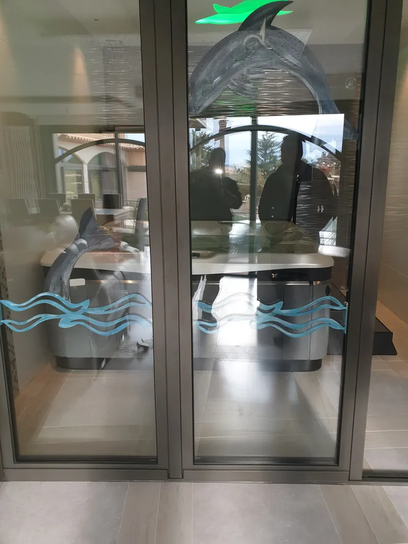 Spa Caldera vu à travers les portes vitrées décorées d'un dauphin de la pièce où il est installé