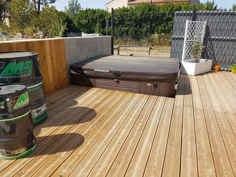 Spa Caldera Geneva à habillage brun semi-encastré dans une terrasse en lames de bois à Gignac