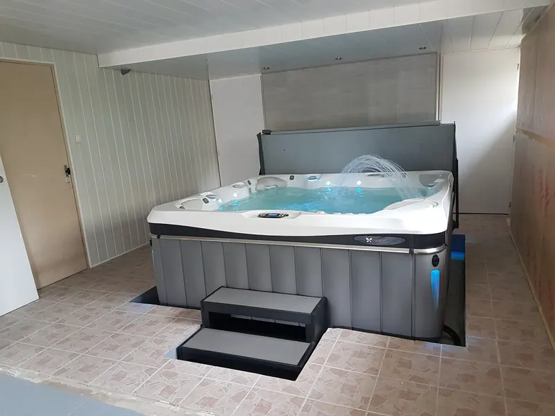 Spa gris en marche avec jet d'eau en arc, marchepied dans la découpe du carrelage, à Marvejols