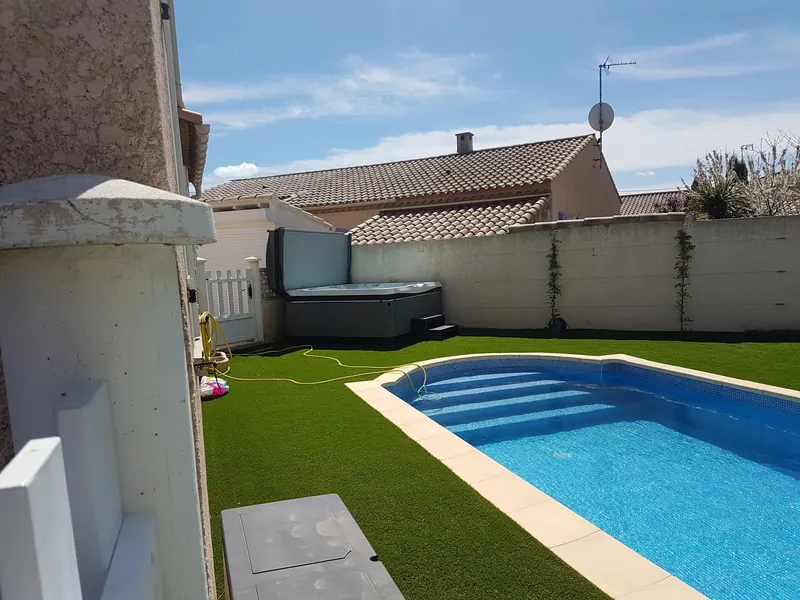 Spa Caldera dans l'angle d'un jardin, vu le long de la piscine à Maureilhan