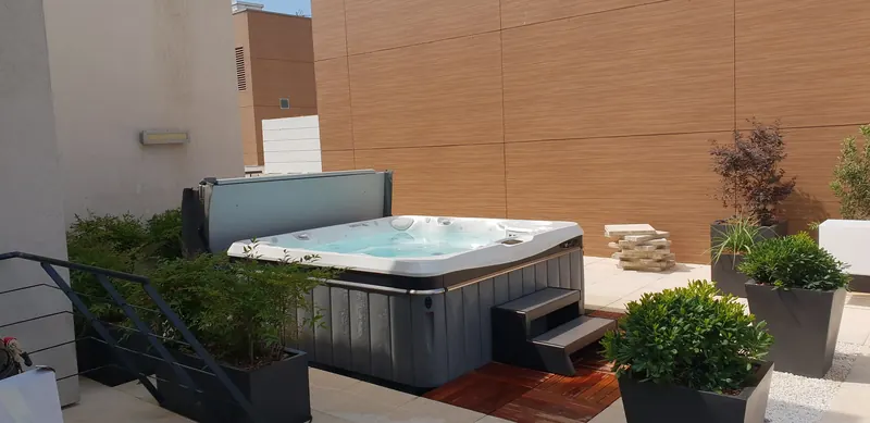 Spa Caldera gris sur un toit-terrasse à Montpellier, entre des bacs plantés, marchepied sur caillebotis en bois