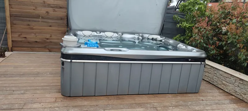 Spa vu de plus près, couverture relevée, caisson gris et badge Caldera Spas