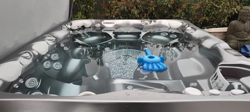 Intérieur du spa : jets, appuie-têtes, fond à motif de galets, jouet flottant bleu