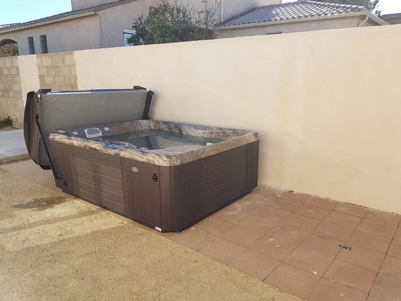 Spa brun posé sur une terrasse carrelée le long d'un mur de clôture enduit à Mèze